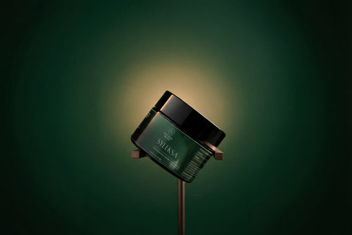 SYLEKSA Nano Herbal Cream jar resting on aged rust-metal surface, single-source studio lighting